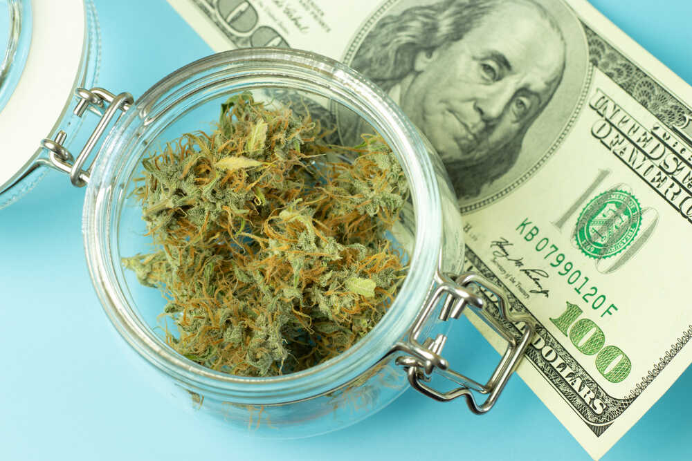 a quarter of weed in a jar on top of a $100 dollar bill